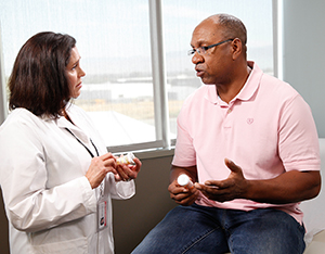 Health care provider talking to man in exam room.