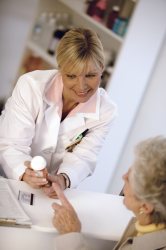 Older woman is talking with a female pharmacist about a bottle of pills.