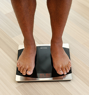 Closeup of man's feet on bathroom scale.