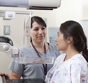 Health care provider positioning woman for mammogram.