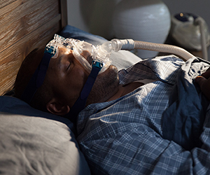 Man in bed wearing CPAP mask.