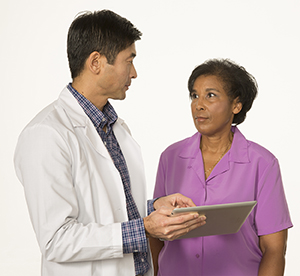 Healthcare provider holding tablet, talking to woman.