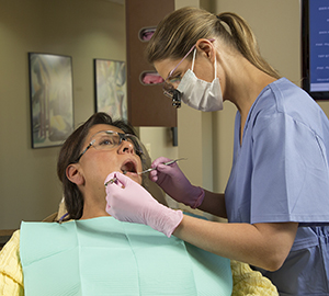 Dental healthcare provider cleaning woman's teeth.