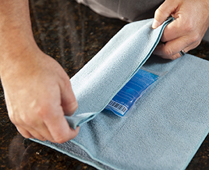 Closeup of man's hands wrapping ice pack in thin towel.