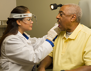 Healthcare provider examining man's mouth.