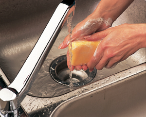 Closeup of hands in sink with running water. Hands are covered with soap suds.