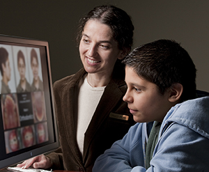 Healthcare provider showing teen boy pictures of his teeth on computer monitor.