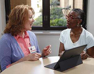 Speech therapist working with woman. Electronic tablet is on table.