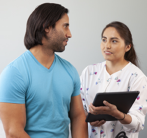 Healthcare provider talking to man in exam room.