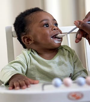 Baby being fed in a high chair.