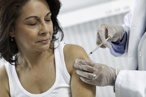 Healthcare provider giving injection in woman's upper arm.