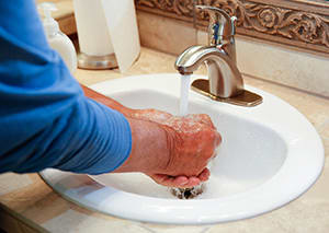 Closeup of male's hands washing with soap in sink.