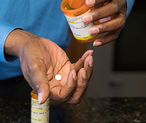 Person's hands holding prescription pill and pill bottle.