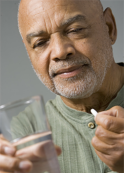 Man taking a pill with a glass of water.