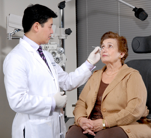 Woman sitting on exam chair. Healthcare provider is examining woman's eye.