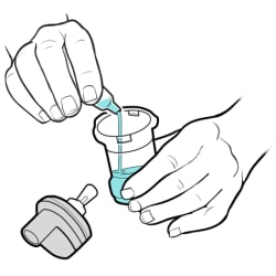 Hand holding cup, with other hand pouring medicine from vial into cup and top of cup lying to the side.