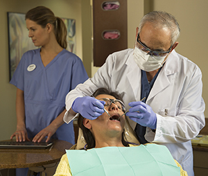 Dental healthcare providers examining woman's teeth.