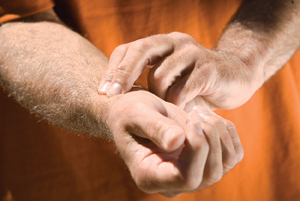 Closeup of man checking pulse with fingers on wrist.