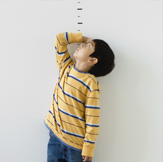 Toddler measuring himself with a drawn ruler on a wall.
