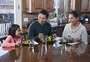 Man, woman, and girl eating healthy food at home.