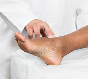 Closeup of healthcare provider examining woman's foot.