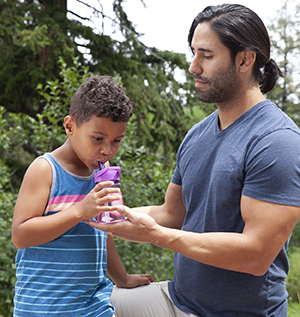 Man giving boy bottle of water.