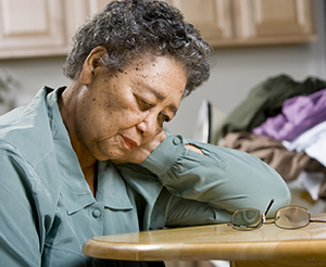 Woman sitting, resting head on hand.