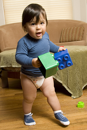 Toddler boy walking with toys.