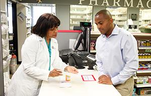 Pharmacist talking to man at pharmacy counter.