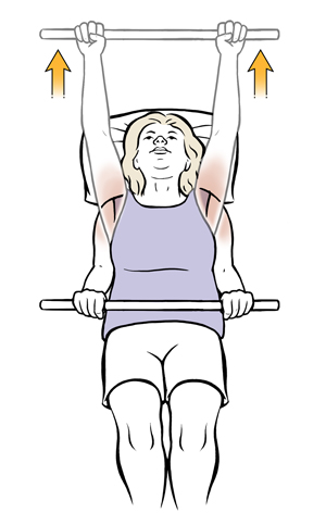 Woman lying on back holding a dowel and lifting it over head in shoulder exercise.