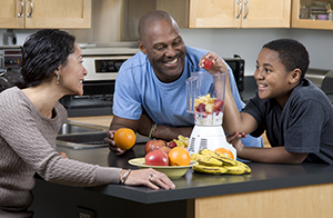 Two adults and teen making fruit smoothies