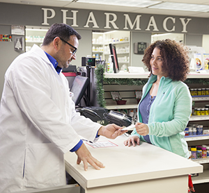Pharmacist talking with woman at pharmacy counter.